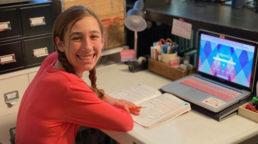 Maddie sitting at her desk with her notebook and laptop open